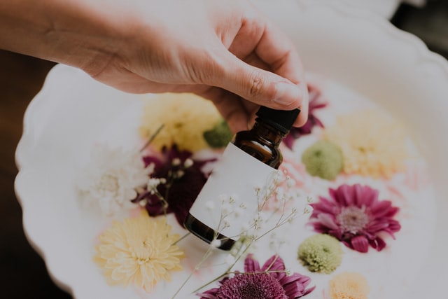 Boccetta di rimedio floreale dei Fiori di Bach con pipetta sopra petali di fiori colorati