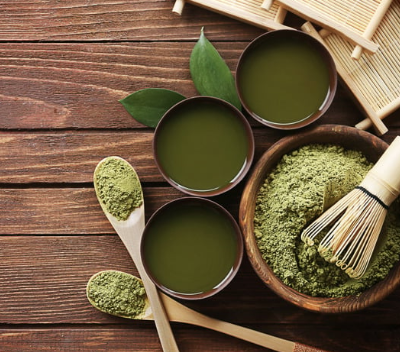 Tazze di tè verde con foglie e polvere di matcha, immagine illustrativa delle proprietà del tè verde e delle tisane naturali.